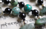 Close up view of 8mm Cuprite, Onyx, and African Turquoise beads. Silver Czech glass beads frame the AT flat chip beads. Black knots protect and showcase the beads.