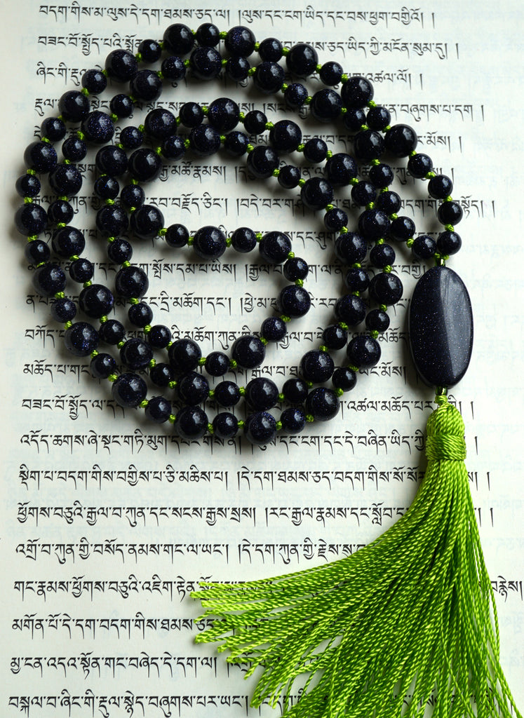 Full view of mala with deep Blue Goldstone beads. The copper crystals in the beads sparkle like the night sky. The apple green sutra and tassel offers a colorful , uplifting contrast to this one-of-a-kind design.