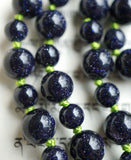Close up view of 6mm and 8mm deep Blue Goldstone beads. The apple green knots between the beads showcase and protect the beads in this one-of-a-kind design.