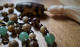 This mala is a beautiful blend of earthy brown beads (Smoky Quartz and Picture Jasper), Green Adventurine and Turquoise chips, Red Garnet  frame White African Opal beads, and earthy red and light brown Dzi Agate rounds and guru bring this eclectic design full circle.