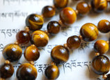 Close up view of warm gold and brown hues of Tiger Eye beads.  The honey gold knots between each bead showcases and protects the beads of this one-of-a-kind design.