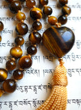 Close up view of 5x25mm heart-shaped gold Tiger Eye guru. A honey gold tassel spills from the base of this focal bead, bringing this design full circle in a beautiful way.