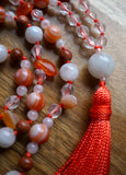 Close up view of 14mm white Moonstone guru with terra cotta tassel spilling from the base, bringing this one-of-a-kind design full circle.