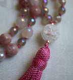 Close up view of 14mm globe-shaped matte Quartz Crystal guru with salmon pink tassel spilling from the base of the bead.
