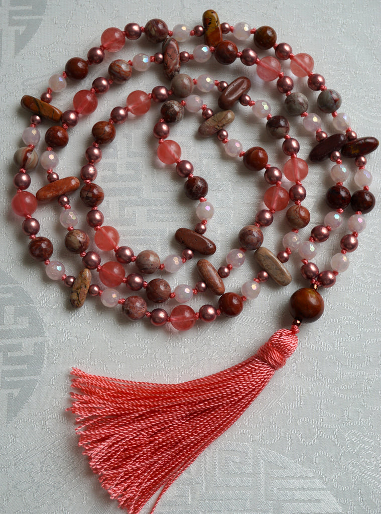 Full view of mala with Red Porcelain Jasper (round and flat chip), dark pink Cherry Quartz, light pink Rose Quartz, and copper Czech glass beads. A Red Porcelain Jasper guru brings this design full circle with a salmon pink tassel spilling from the base. This hand-knotted mala is a one-of-a-kind design.
