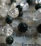 Close up view of 8mm clear Crackle Quartz Crystal beads; deep forest green Seraphinite beads (6mm and 8mm) with feathery white and silver inclusions. White knots protect and showcase the beads.