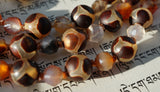 Close up view of 8mm Turtle Agate beads: translucent , light brown beads with dark brown, "shell-like" patterns  and 6mm star-cut Madagascar Dendritic Agate beads: opaque stones in shades of milky white, orange, yellow, brown and gray. Between each bead is a variegated brown knot. The knots protect and showcase the beads in this one-of-a-kind design.