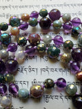 Close up view of purple Amethyst, shimmering, faceted Jasper beads in light brown, green, and lavender. Lavender knots connect, showcase, and protect each bead.
