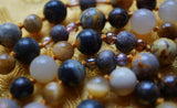 Close up view of 8mm Bumblebee Jasper, 6mm Gray wood framed with 4mm Czech glass, Bronzite, and Goldeneye beads. Goldenrod knots between each bead offer strength and support as well as showcase the beads in this design..