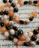 Close up view of beads: 6mm Peach Moonstone, Porcelain Jasper, Sardonyx; 6x8mm rice-shaped Onyx, 6mm faceted White Jade.