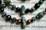 Close up view of 5x15mm African Turquoise flat chip beads (turquoise blue green with black and brown colorations). 8mm and 6mm faceted black Onyx beads. 6mm copper Czech glass beads. Black knots between each bead or bead unit protect beads from chipping and cracking via friction.