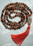 Full view of mala with Orange Agate, gray Botswana Agate, brown Smoky Quartz, gray Chalcedony beads with a white Chalcedony guru and soft peach sutra and tassel.  