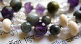 Close up view of faceted Amethyst, gray Cat's Eye, Pine rondelle beads framed with Lavender Amethyst, and white Crackle Quartz beads. Cream-colored knots protect and showcase the beads of this design beautifully.