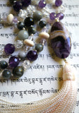 Close up view of 15x30mm Chevron Amethyst guru with a cream-colored tassel spilling from the base of the bead.