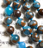 Close up view of 8mm blue and brown Mosaic Quartz beads and dark brown Bronzite beads. Marine blue knots between the beads protect and showcase the beads of this one-of-a-kind mala design.