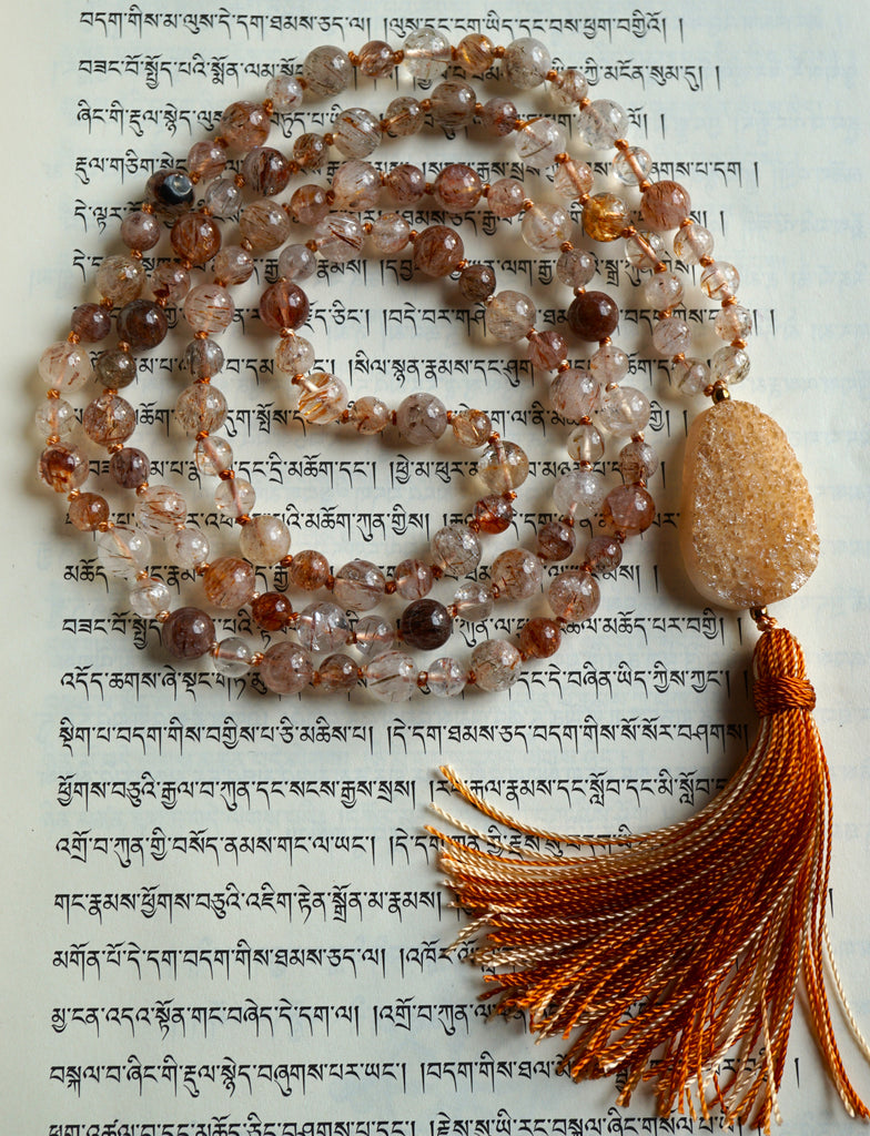 Full view of mala with brown Rutilated Quartz beads and a cream-colored Druzy Agate guru with cinnamon brown variegated sutra/tassel.