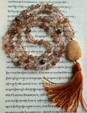 Full view of mala with brown Rutilated Quartz beads and a cream-colored Druzy Agate guru with cinnamon brown variegated sutra/tassel.
