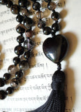 Close up view of 5x25mm heart-shaped Obsidian guru. A black tassel spills from the base of this powerful focal bead.