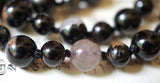 Close up view of Calico Tourmaline beads in black, brown, and white hues. The black knots between beads protect and showcase the beads of this design beautifully.