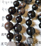 Close up view of Calico Tourmaline beads with black, brown, and white hues. The black knots between the beads protect and showcase beautifully the beads of this one-of-a-kind design.