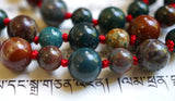 Dragon Blood Jasper beads are primarily deep green in color with variations of red and brown striations and inclusions.