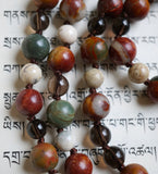 Close up view of Red Creek Jasper, Smoky Quartz, and White African Opal beads. The chocolate brown knots protect and showcase the beads of this beautiful design.