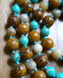 Close up view of brown Elephant Jasper beads with dark brown swirls that resemble elephant skin and light blue Aqua Impression Jasper beads with light brown and cream colored vein-like inclusions. Sky blue knots between the beads protect and showcase the beads of this one-of-a-kind design.