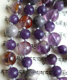 Close up view of the purple beads of this hand-knotted mala. Silver knots between the beads protect and showcase beautifully the beads in this design.