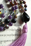 Close up view of teardrop-shaped black Onyx guru. A lilac tassel spills from the base of this focal bead, bringing this design full circle.