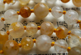 Close up view of Golden Healer Quartz beads. Range in color from white to soft yellow to golden brown. Honey gold knots between the beads protect and showcase the beads of this one-of-a-kind design.