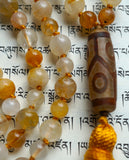 Close up view of 12x24mm Dzi Agate guru with light and dark brown colors and geometric design. 