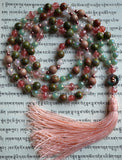 This mala includes a blend of pink and green beads .