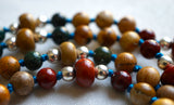 Close up view of 8mm Red Jasper rondelle bead framed with 4mm silver Czech glass. Two 6mm Apple Jasper rounds and earthy brown Picture Jasper beads; green Fancy Jasper; 8mm Wood Jasper framed with silver Czech glass. The marine blue knots between protect and showcase the beads of this design.