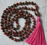 Full view of Kashgar Garnet Mala. Pink and green Kashgar Garnet beads. Hand-knotted with mauve sutra (cord). A brown and cream barrel-shaped guru brings this design full circle. A mauve tassel spills from the base of the guru.