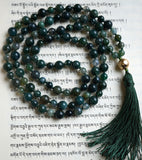 Full view of Moss Agate Mala with dark green Moss Agate beads and 12mm textured gold metal guru. A forest green tassel spills from the base of the guru of this hand-knotted mala.