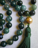 Close up view of 12mm textured gold metal guru. A Forest green tassel spills from the base of this bead, bringing this design full circle.