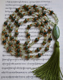 Light green Prehnite beads combine with dark green Olivine Jade rondelles framed with translucent topaz Czech glass beads. A 15x30mm oval Jade guru brings this hand-knotted design full circle with olive green tassel.