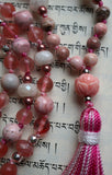 Close up view of 12mm pink lotus guru with variegated pink tassel spilling from the base of this focal bead.