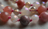 Close up view of 8mm Pink Tourmaline beads framed with 6mm White Agate beads. The bright pink knots between the beads protect against friction and showcase the beads beautifully.