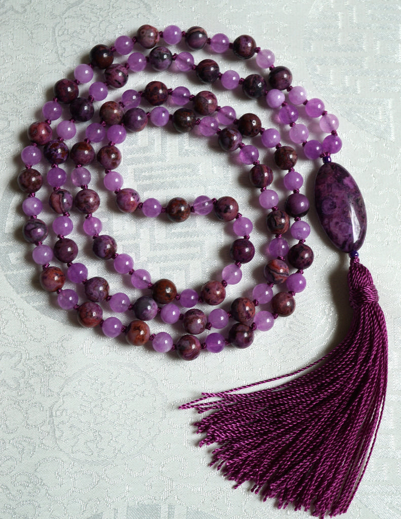 Full view of mala with 8mm Purple Crazy Lace Agate. These vibrant purple beads with swirling patters and whorls combine with the lighter purple 6mm Jade beads. An oval Purple Crazy Lace Agate guru brings this hand-knotted design full circle, along with a bright purple tassel.