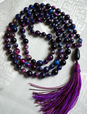 Full view of bold blue, purple, pink, and green Rainbow Tiger Eye beads with teardrop-shaped Onyx guru and variegated purple tassel.