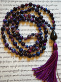 Full view of hand-knotted Rainbow Tiger Eye Mala with black teardrop-shaped guru and variegated purple tassel.