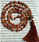 Full view of mala with red orange Botswana Agate, smoky gray, white, and orange Madagascar Dendritic Agate beads, rose gold crystals, and a spunky, funky copper "disco ball" guru with cinnamon brown sutra and tassel.