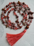 Full view of mala with Red Porcelain Jasper (round and flat chip), dark pink Cherry Quartz, light pink Rose Quartz, and copper Czech glass beads. A Red Porcelain Jasper guru brings this design full circle with a salmon pink tassel spilling from the base. This hand-knotted mala is a one-of-a-kind design.