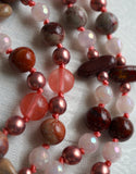 Close up view of 8mm Red Porcelain Jasper beads (round and flat chip) with red, gray, pink, and burgundy colors; translucent dark pink Cherry Quartz; light pink faceted Rose Quartz; copper Czech glass beads . Salmon pink knots between beads and bead units protect and showcase the beads of this design.