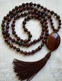 Full view of Red Tiger Eye Mala. Alternating 6mm and 8mm deep red Tiger Eye beads with 15x30mm oval Red Tiger Eye guru and chocolate Brown sutra and tassel.
