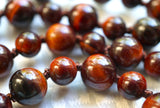 Close up view of Red Tiger Eye beads with chocolate brown knots between to showcase and protect the beads of the design.