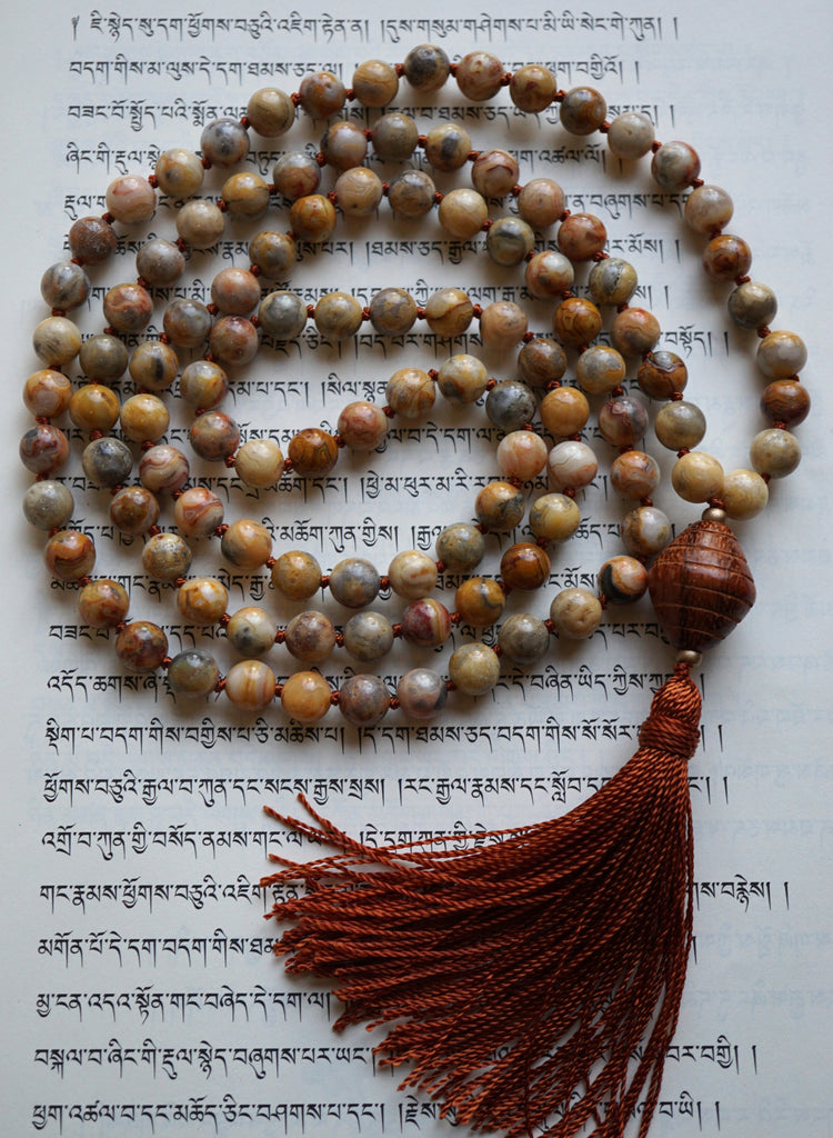 Full view of mala with 108, 8mm Sage Agate beads  in warm, earthy hues. A  light brown, bicone-shaped  wooden bead (Bayong) brings this hand-knotted design full circle with a cinnamon brown tassel spilling from the base of the guru bead.