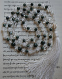 Full view of Tara Mala. 8mm clear Crackle Quartz Crystal, 8mm and 6mm deep forest green Seraphinite beads with silvery white feather-like inclusions, 6mm starcut Quartz Crystal beads,  and 14mm Tribe Hill silver honeycomb guru.  This hand-knotted mala has white knots between each bead, and a white tassel spilling from the base of the guru.
