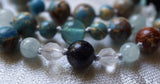 close up view of dark Blue Goldstone (with flecks of reflective copper) framed with 6mm star-cut Quartz Crystal beads, light blue Aquamarine, and Aqua Impression Jasper beads (light blue with light brown inclusions).